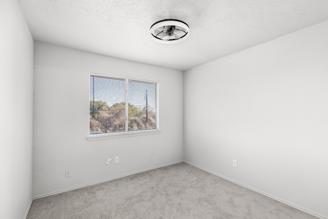 spare room with light colored carpet and a textured ceiling