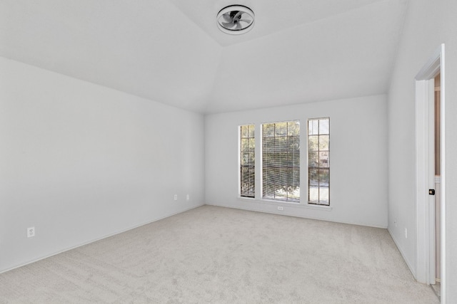 spare room featuring lofted ceiling and light carpet