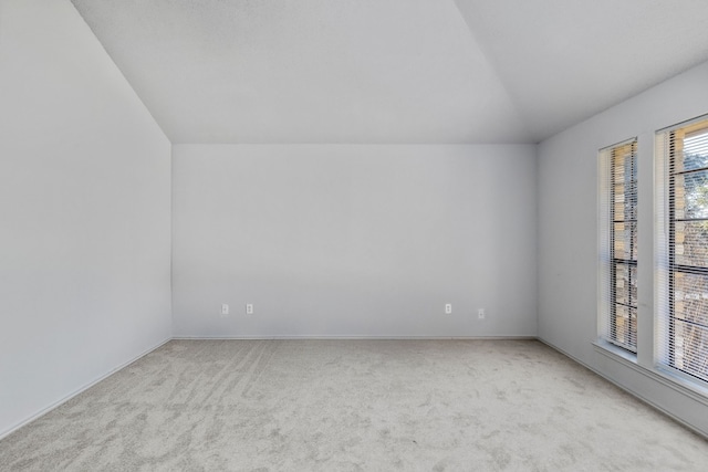 carpeted spare room with vaulted ceiling