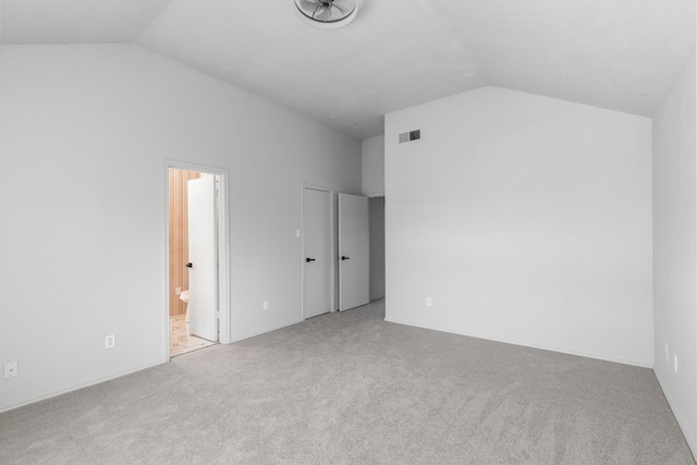 unfurnished bedroom with light colored carpet, lofted ceiling, and ensuite bathroom