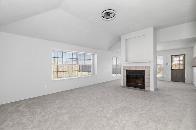 unfurnished living room featuring lofted ceiling, plenty of natural light, and a tile fireplace