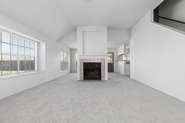 unfurnished living room with lofted ceiling, a fireplace, light colored carpet, and plenty of natural light