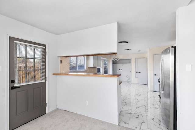 kitchen featuring white cabinetry, stainless steel fridge, and kitchen peninsula