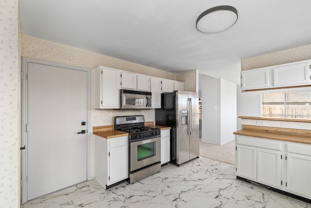 kitchen featuring wood counters, stainless steel appliances, and white cabinets