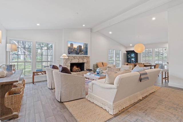 living room featuring a fireplace, light hardwood / wood-style floors, and lofted ceiling with beams