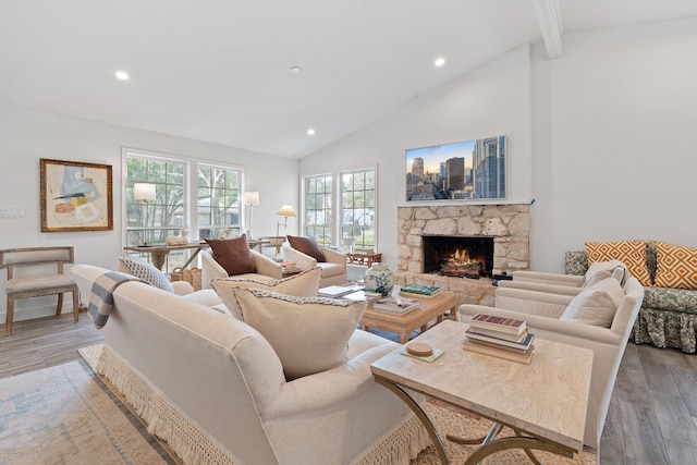 living room featuring a stone fireplace, high vaulted ceiling, beam ceiling, and light hardwood / wood-style flooring