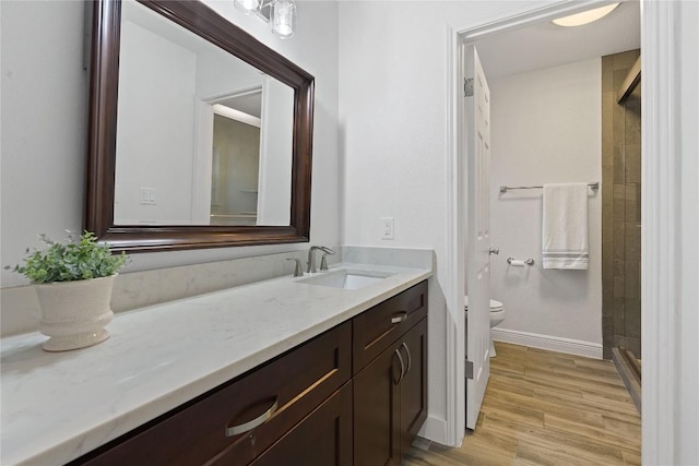 bathroom with vanity, toilet, hardwood / wood-style floors, and a shower