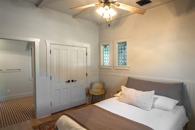 bedroom with beamed ceiling, ceiling fan, and a closet