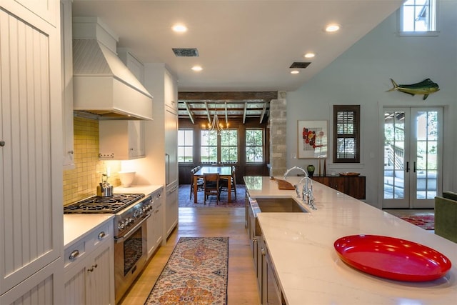 kitchen featuring french doors, sink, custom exhaust hood, stainless steel stove, and white cabinets