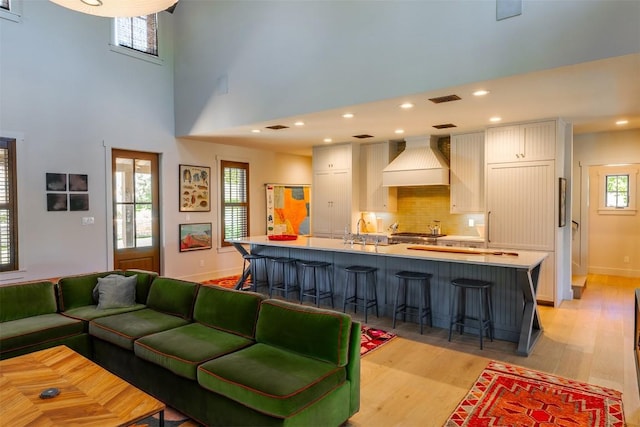 living room with sink, light hardwood / wood-style flooring, and a high ceiling