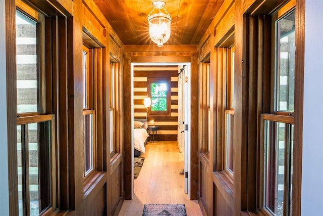 hall with wood ceiling, wooden walls, and light wood-type flooring