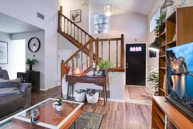 entrance foyer with wood-type flooring, high vaulted ceiling, and a textured ceiling