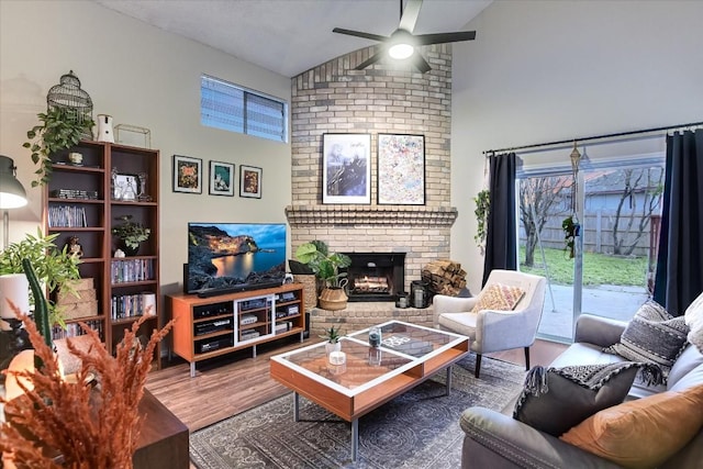 living room with wood-type flooring, a brick fireplace, high vaulted ceiling, and ceiling fan