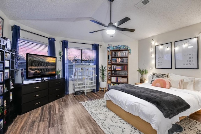 bedroom featuring lofted ceiling, ceiling fan, dark wood-type flooring, and a textured ceiling