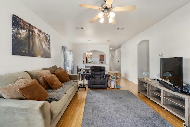 living room with ceiling fan with notable chandelier and light wood-type flooring