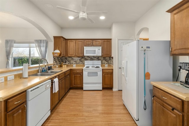 kitchen featuring sink, white appliances, ceiling fan, light hardwood / wood-style floors, and backsplash