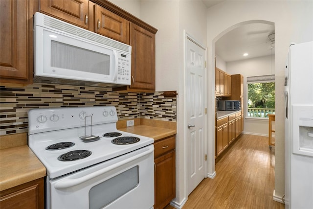 kitchen featuring ceiling fan, white appliances, light hardwood / wood-style floors, and decorative backsplash