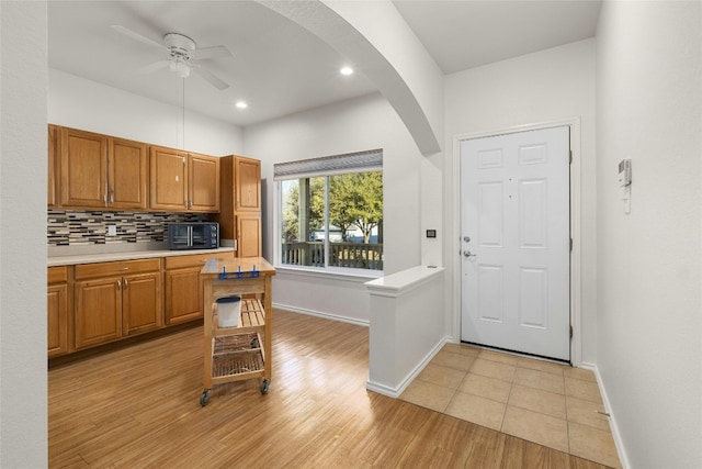 kitchen with decorative backsplash, ceiling fan, and light wood-type flooring