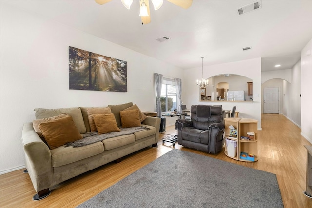 living room featuring ceiling fan with notable chandelier and hardwood / wood-style floors