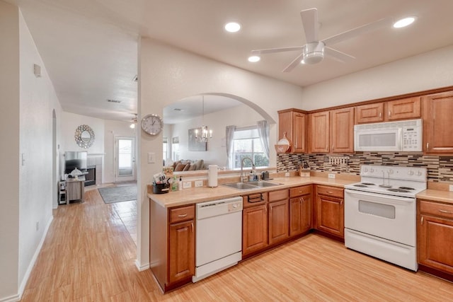 kitchen featuring tasteful backsplash, ceiling fan with notable chandelier, white appliances, and a sink