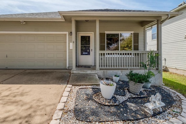entrance to property with a garage, roof with shingles, covered porch, and driveway