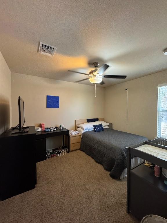 bedroom featuring carpet, a textured ceiling, and ceiling fan