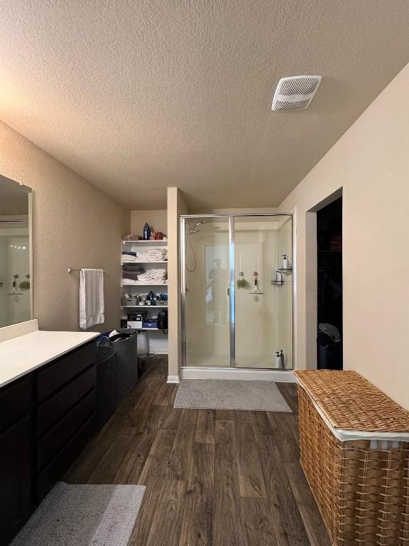 bathroom featuring vanity, hardwood / wood-style flooring, a shower with door, and a textured ceiling