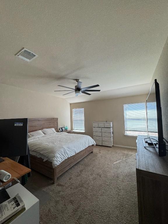 bedroom featuring ceiling fan, carpet flooring, and a textured ceiling