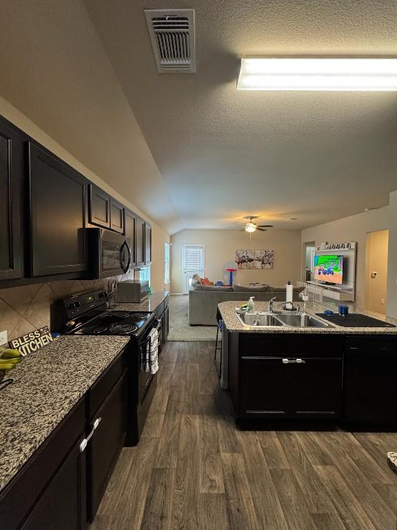 kitchen featuring sink, dark hardwood / wood-style flooring, electric range, light stone countertops, and a textured ceiling