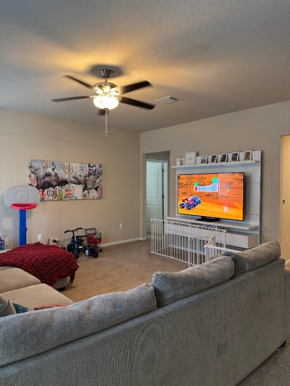 living room with a textured ceiling, ceiling fan, and carpet flooring