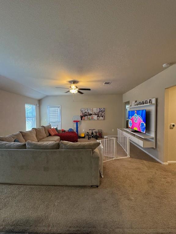 living room with ceiling fan, a textured ceiling, and carpet