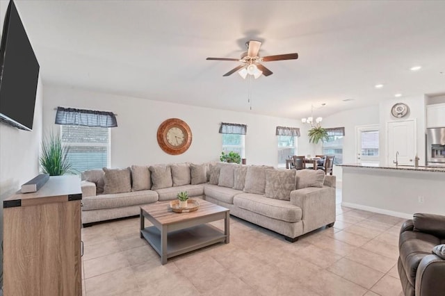 tiled living room with ceiling fan with notable chandelier and vaulted ceiling