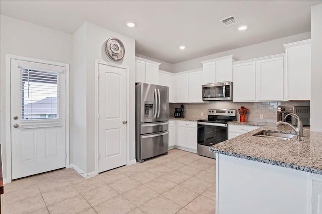 kitchen featuring stainless steel appliances, light stone countertops, sink, and white cabinets