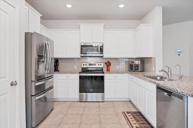 kitchen featuring light stone counters, backsplash, white cabinetry, and appliances with stainless steel finishes