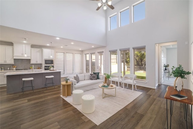 living room with dark wood-type flooring, ceiling fan, and plenty of natural light