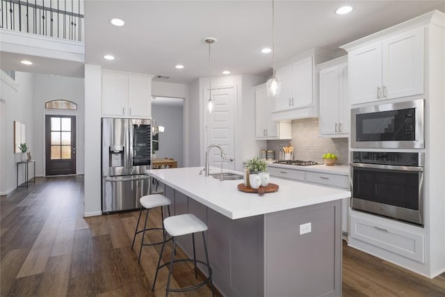 kitchen with dark hardwood / wood-style floors, white cabinetry, sink, a kitchen island with sink, and stainless steel appliances