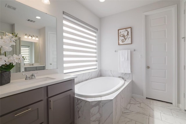 bathroom with a relaxing tiled tub and vanity