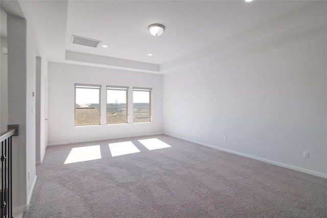 carpeted spare room featuring a tray ceiling