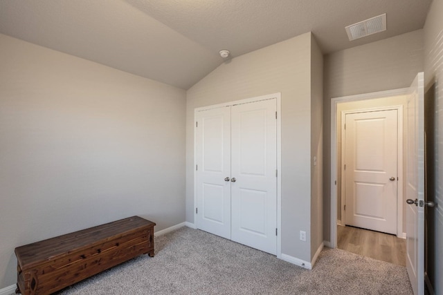 carpeted bedroom with lofted ceiling and a closet