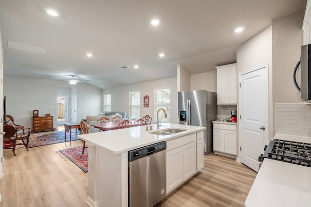 kitchen featuring sink, appliances with stainless steel finishes, white cabinets, a center island with sink, and light wood-type flooring