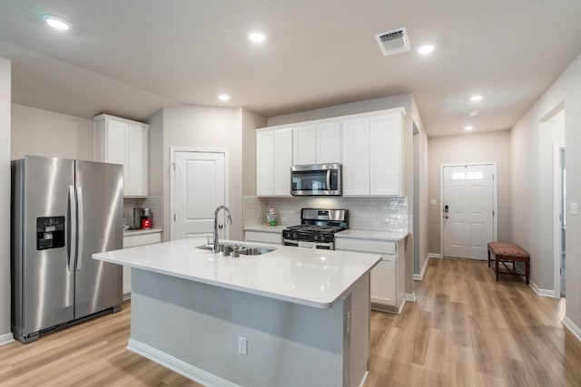 kitchen with a kitchen island with sink, sink, white cabinets, and appliances with stainless steel finishes