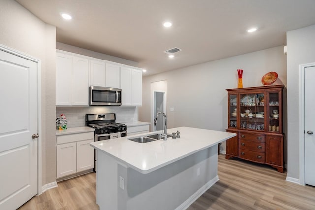 kitchen featuring an island with sink, stainless steel appliances, sink, and white cabinets