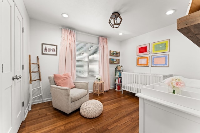 bedroom featuring dark wood-type flooring and a crib