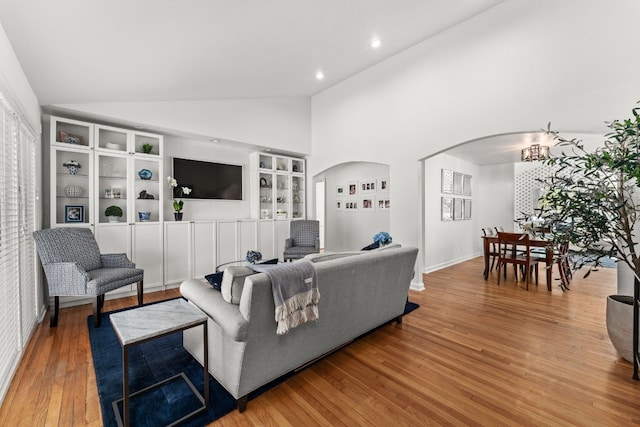 living room with wood-type flooring, high vaulted ceiling, and built in shelves