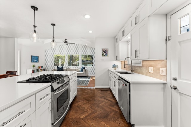 kitchen with pendant lighting, sink, appliances with stainless steel finishes, dark parquet floors, and white cabinets