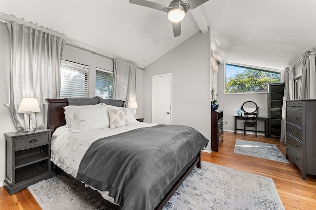 bedroom with ceiling fan, light hardwood / wood-style floors, and vaulted ceiling with beams