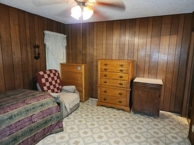 bedroom featuring ceiling fan, wooden walls, and a textured ceiling