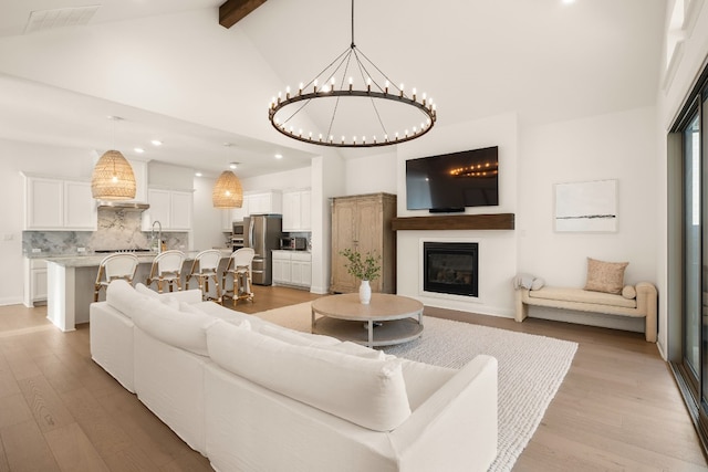 living room featuring a notable chandelier, beam ceiling, high vaulted ceiling, and light wood-type flooring