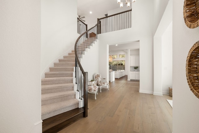 entrance foyer with hardwood / wood-style flooring, a towering ceiling, and a chandelier