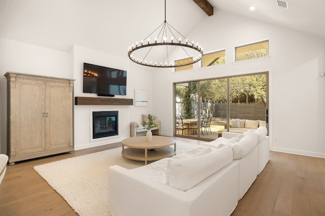 living room with beamed ceiling, a chandelier, high vaulted ceiling, and light wood-type flooring